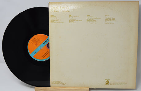 Vinyl record with orange label and beige record cover on a white background