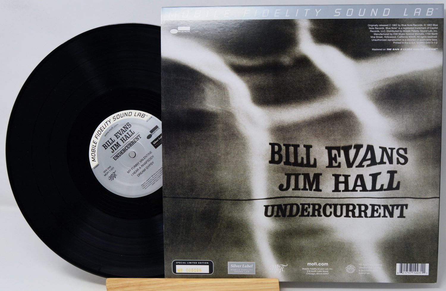 Vinyl record album shown with the black record partially pulled from the sleeve, photographed on a light gray background. The sleeve features a black-and-white abstract design with the text 'Bill Evans Jim Hall Undercurrent' and 'Prelude Sound Lab' at the top.