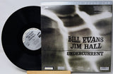 Vinyl record album shown with the black record partially pulled from the sleeve, photographed on a light gray background. The sleeve features a black-and-white abstract design with the text 'Bill Evans Jim Hall Undercurrent' and 'Prelude Sound Lab' at the top.
