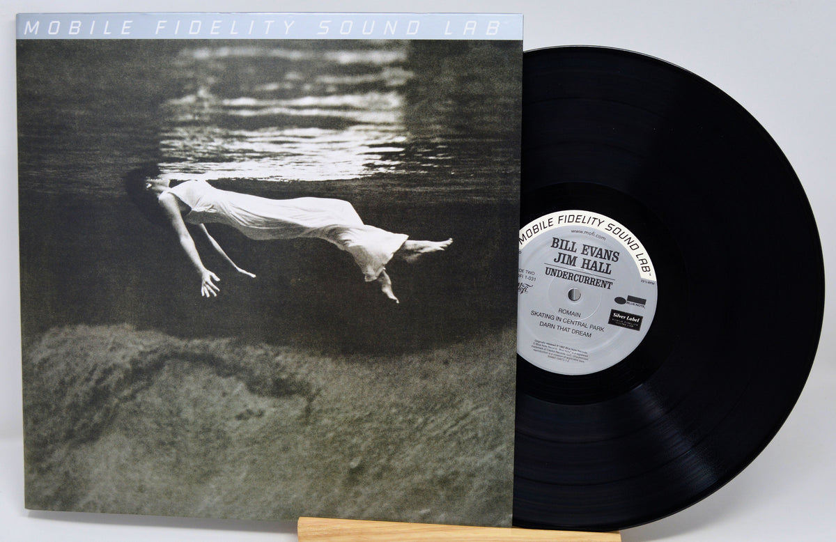 Vinyl record album 'Unburdened' by Bill Evans and Jim Hall, featuring the black LP disc partially pulled from the sleeve, which displays a black-and-white underwater photograph of a woman floating on her back.
