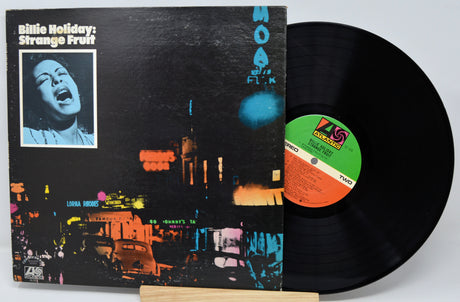 Vinyl record with cover featuring a cityscape and a person's face, on a light gray background.