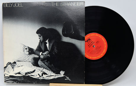 Billy Joel's 'The Stranger' vinyl record LP with its cover sleeve and the black vinyl disc partially pulled out, set against a plain light background.