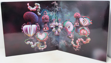 A square art print or poster displayed open against a white surface, featuring surreal abstract organic forms in pink, purple, teal, and cream on a dark background.