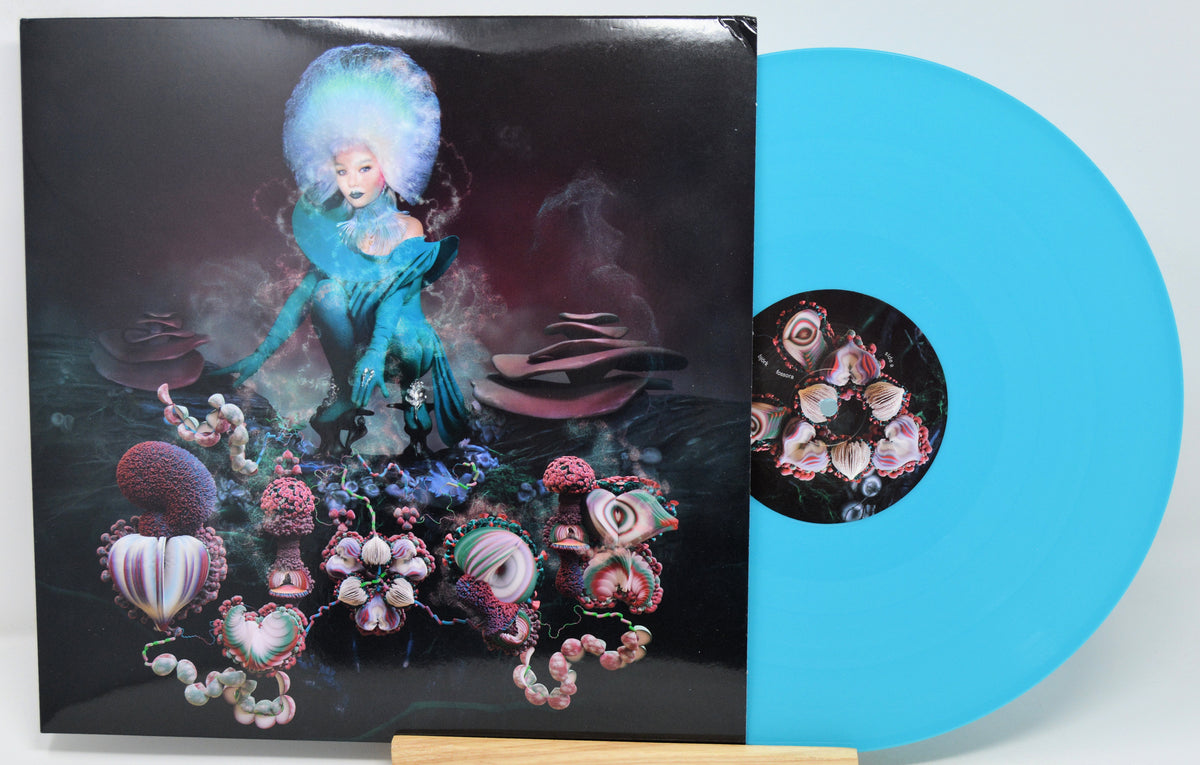 A vinyl record partially pulled from its sleeve, showing a bright cyan-blue disc alongside the illustrated album cover.