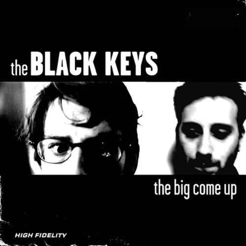This image features the album cover for "The Big Come Up" by The Black Keys, a debut album released in 2002. The cover art is strikingly simple, displaying a blurred, monochrome photo of the band members, Patrick Carney and Dan Auerbach, with the band's name in bold, white text above.