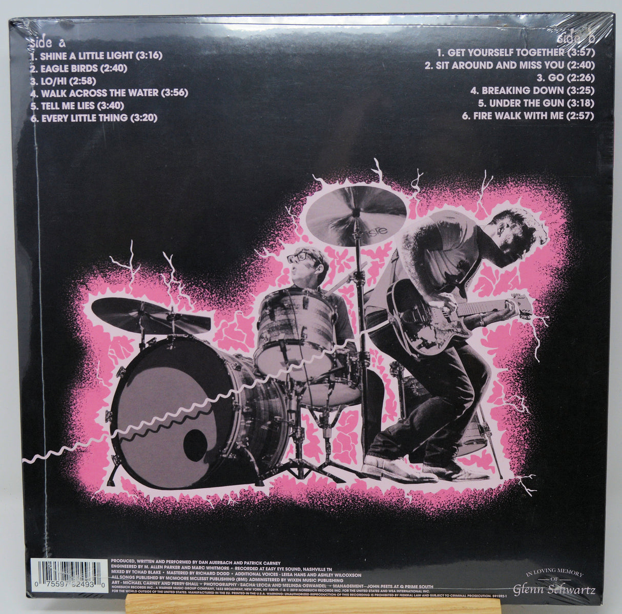 Vinyl record sleeve with black and white illustration of a band playing instruments on a pink background.
