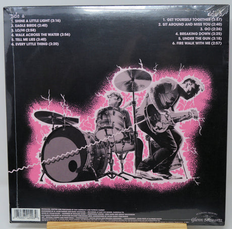 Vinyl record sleeve with black and white illustration of a band playing instruments on a pink background.