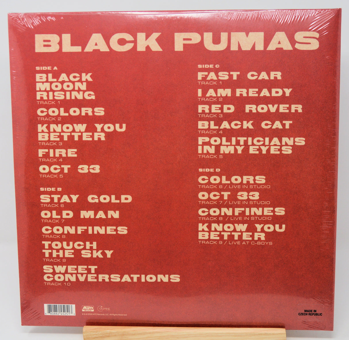 Black Pumas 'Colors' vinyl record album cover back, shown shrink-wrapped on a wooden display stand against a white background.