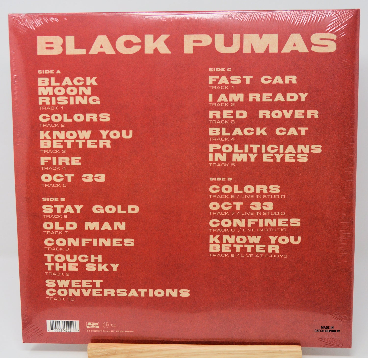 Black Pumas 'Colors' vinyl record album cover back, shown shrink-wrapped on a wooden display stand against a white background.