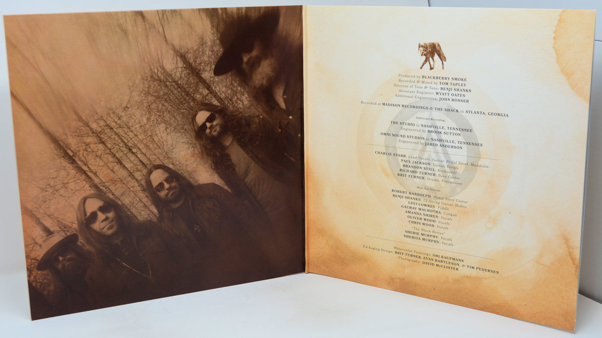 An open vinyl record sleeve or album booklet showing printed cover art on the left panel and track listing on the right panel, photographed on a white surface.