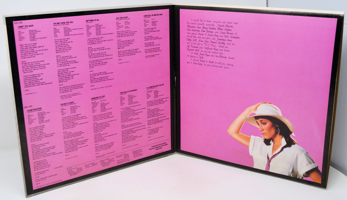 Album cover with pink background and text on the left, featuring a person on the right.