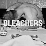 Person lying face down on a talbe with no shirt on 'BLEACHERS' text overlay