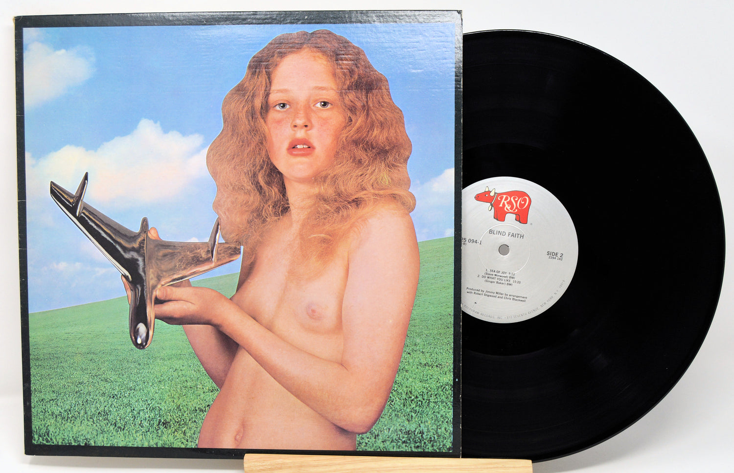 Vinyl record with a cover featuring a stylized depiction of a person holding a tool, set against a blue sky and green field.