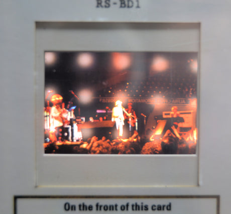 Concert scene with Bob Dylan on stage and a crowd, framed by a border with text.