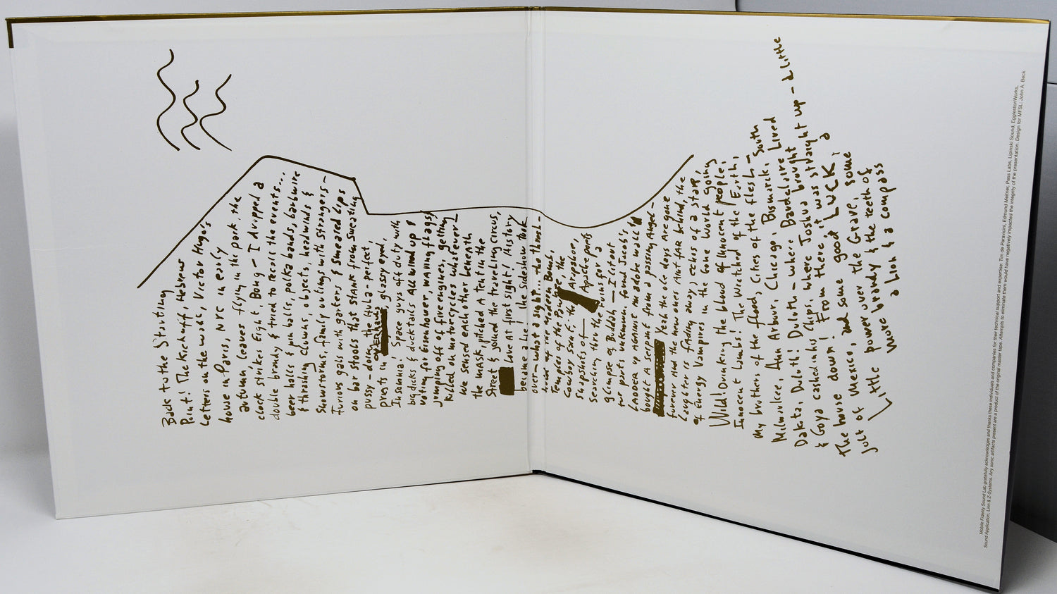 An open book or printed booklet on a white surface, showing a detailed topographic-style map drawn in brown ink with handwritten text throughout the pages.