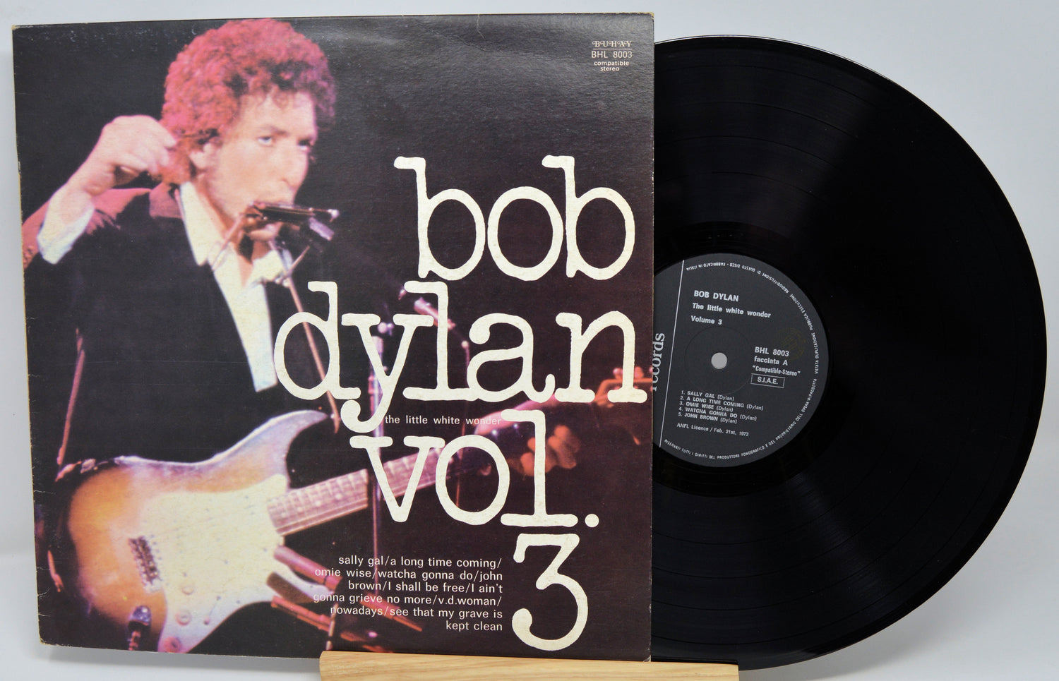 Vinyl record with cover featuring Bob Dylan holding a guitar, on a white background