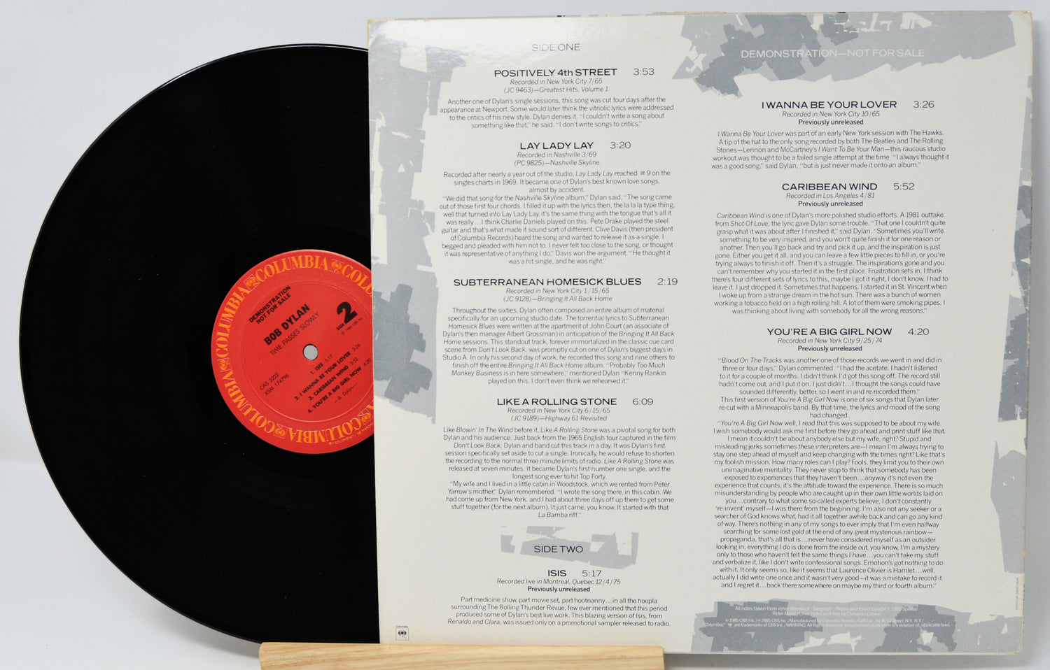 Vinyl record with a red label and its cover displaying track listings on a light gray background