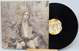 Vinyl record with a cover featuring a person and a colorful label on a white background