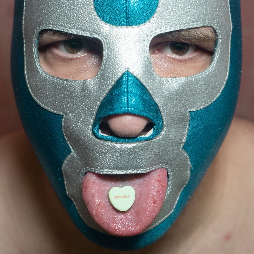 Vinyl record cover with a person wearing a blue and silver wrestling mask with a heart-shaped candy in their mouth that has 'New Self' on it.