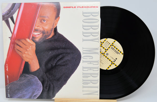 Vinyl record with cover featuring a man holding a red object, titled 'Simple Pleasures' by Bobby McFerrin.