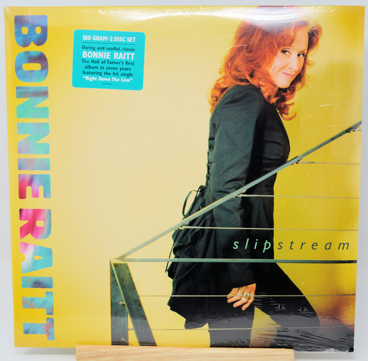 Bonnie Raitt's 'Slipstream' 2-CD box set vinyl record cover, sealed in plastic shrink wrap, displayed on a wooden stand against a white background.