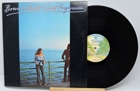 Vinyl record with cover featuring a couple by the sea, titled 'Bonnie Raitt - Sweet Forgiveness'.