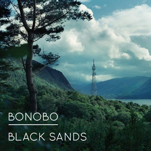 Cover art for Bonobo album 'Black Sands' featuring a landscape image with a tree and a radio tower in the background, indicating a serene and natural setting.