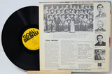 Vinyl record with a yellow label and a photo sleeve featuring a group of people.