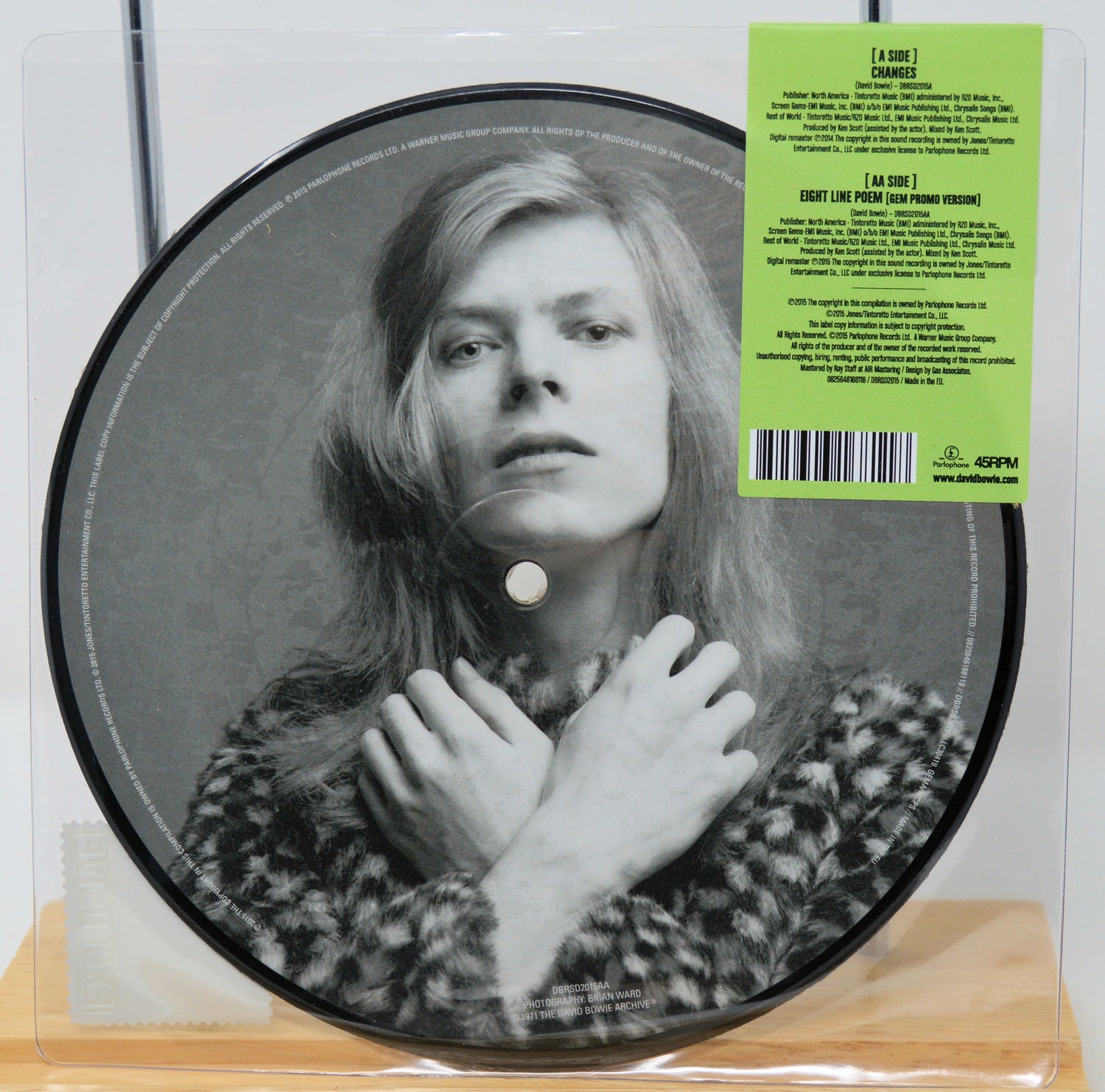 Picture disc vinyl with a black and white portrait and green label on a wooden surface