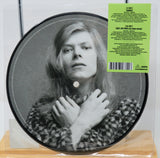 Picture disc vinyl with a black and white portrait and green label on a wooden surface