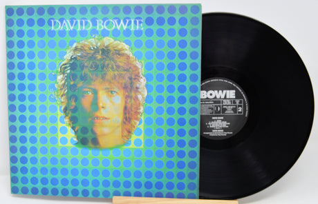 Vinyl record with cover featuring a portrait and 'David Bowie' text on a blue and green polka dot background.