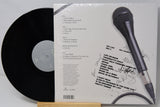 Vinyl record with a microphone on top, placed on a white surface.