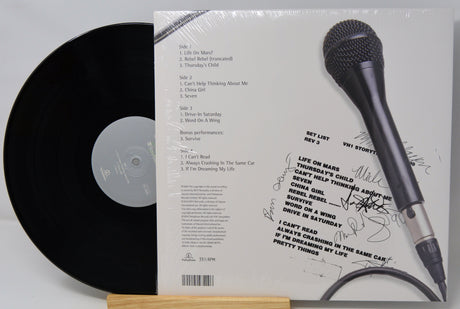 Vinyl record with a microphone on top, placed on a white surface.