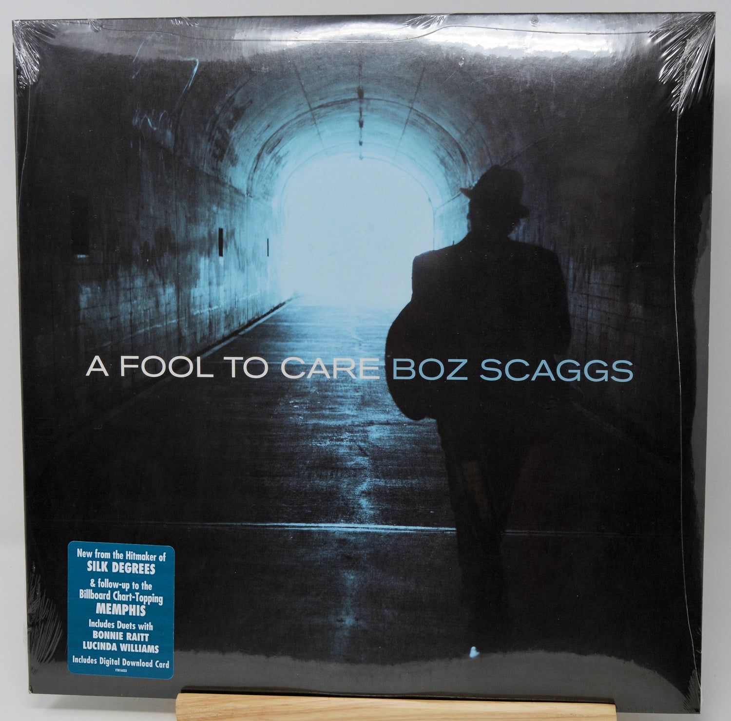 Boz Scaggs 'A Fool to Care' vinyl record album in shrink wrap, displayed on a wooden stand against a white background.