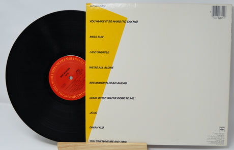 Vinyl record with yellow label and white sleeve on a white background