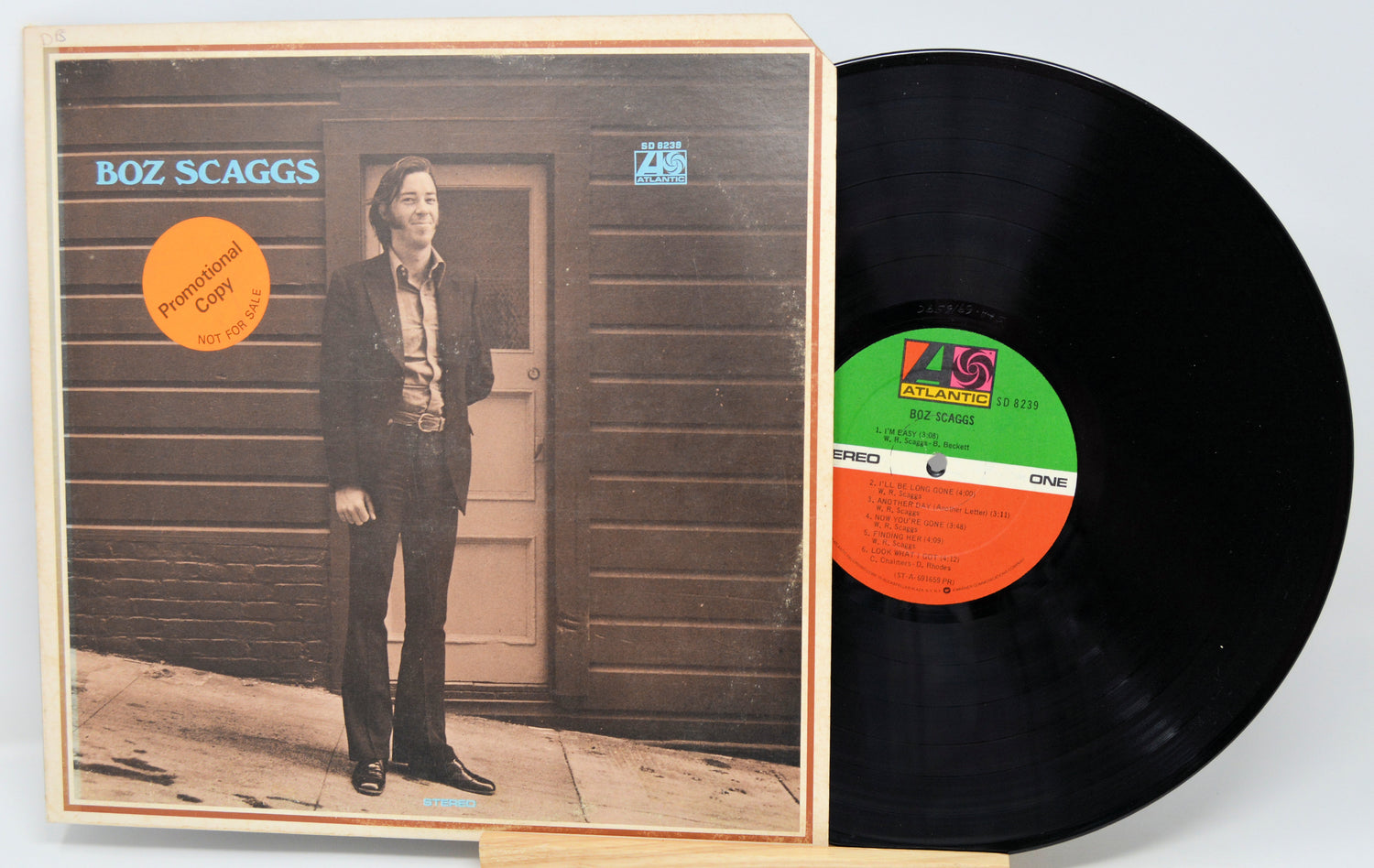 Vinyl record with cover featuring a person standing in front of a wooden door.