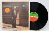 Vinyl record with cover featuring a person standing in front of a wooden door.