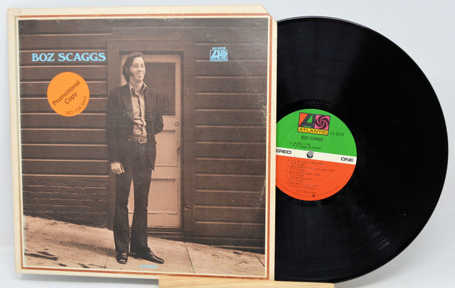 Vinyl record with cover featuring a person standing in front of a wooden door.
