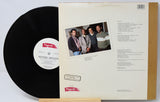 Vinyl record with cover featuring a group of people and album details.