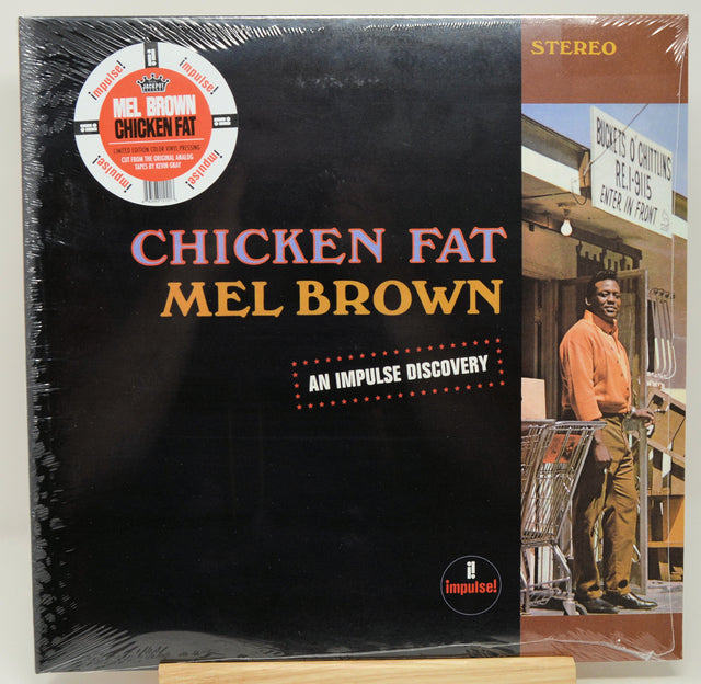 Mel Brown's 'Chicken Fat' vinyl record LP on Impulse Records, sealed in plastic shrink wrap. The cover is predominantly black with orange and pink text, and features a color photograph of Mel Brown on the right side.