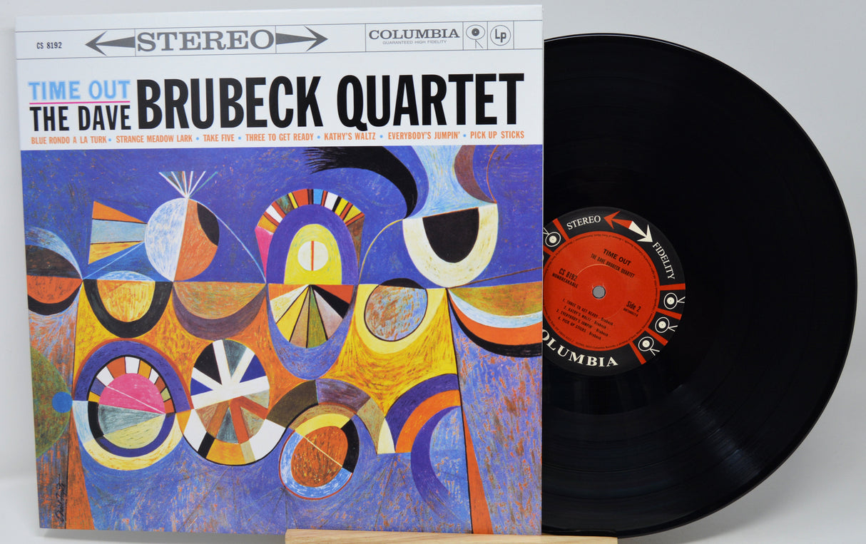 Vinyl record album for 'Time Out' by The Dave Brubeck Quartet, showing the illustrated cover on the left and the black record partially pulled out on the right. Columbia branding is visible on both the cover and the center label.