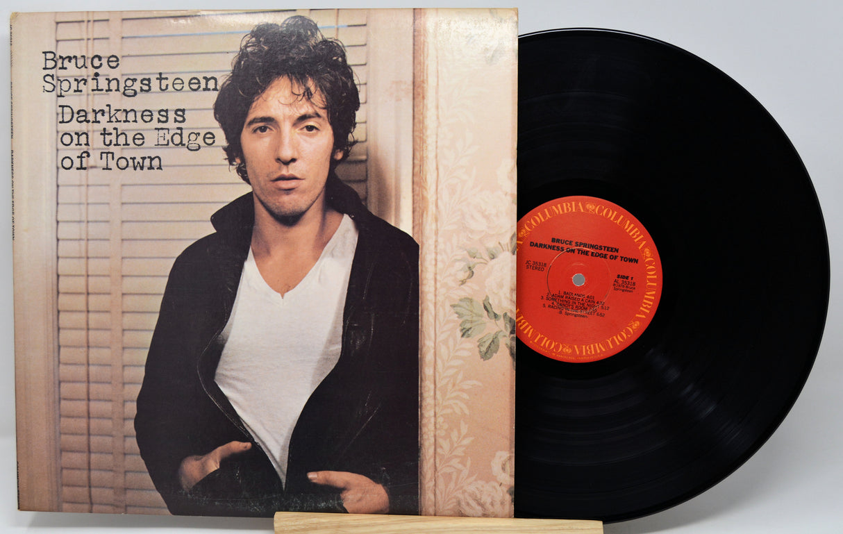 Bruce Springsteen's 'Darkness on the Edge of Town' vinyl record album with the LP partially pulled from the jacket, showing the black record and orange center label.