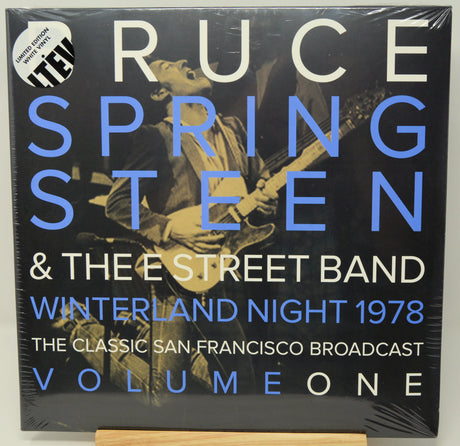 Vinyl record album cover for 'Ruce Springsteen & The Street Band Winterland Night 1978' on a black background with large blue and white text and a photo of a musician playing guitar. The album is wrapped in plastic and photographed on a wooden stand against a white background.