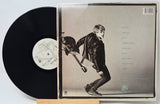 Vinyl record with its cover featuring a person playing guitar on a light background