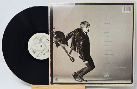 Vinyl record with its cover featuring a person playing guitar on a light background
