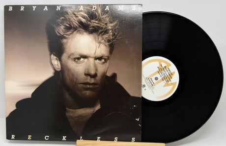 Vinyl record with cover featuring a portrait and album title 'Reckless' by Bryan Adams.