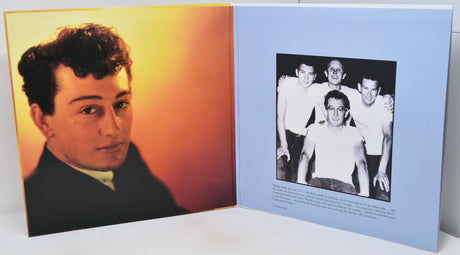 An open book or photo album showing two printed pages: one with a warm-toned portrait of a man and the other with a black-and-white group photo and small text on a light blue page.