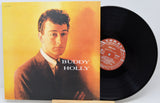 Buddy Holly vinyl record album with the LP partially pulled from the jacket sleeve, showing the black record and the cover art on a light gray background.