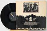 Vinyl record with its cover featuring a black and white photo of three people and text.