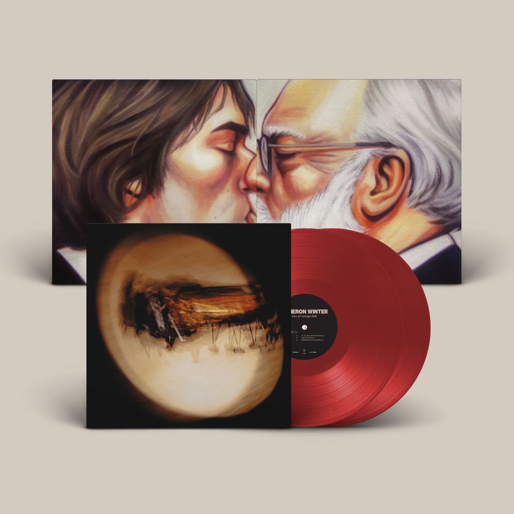 A vinyl record album shown on a light beige background, featuring a large illustrated cover with two faces leaning in close, a smaller square insert with a circular abstract artwork, and a translucent red vinyl record partially visible behind it.